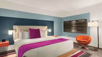Ein modernes Hotelzimmer mit einem großen Bett, einem Nachttisch, einem Sessel und einem an der Wand befestigten Schild.