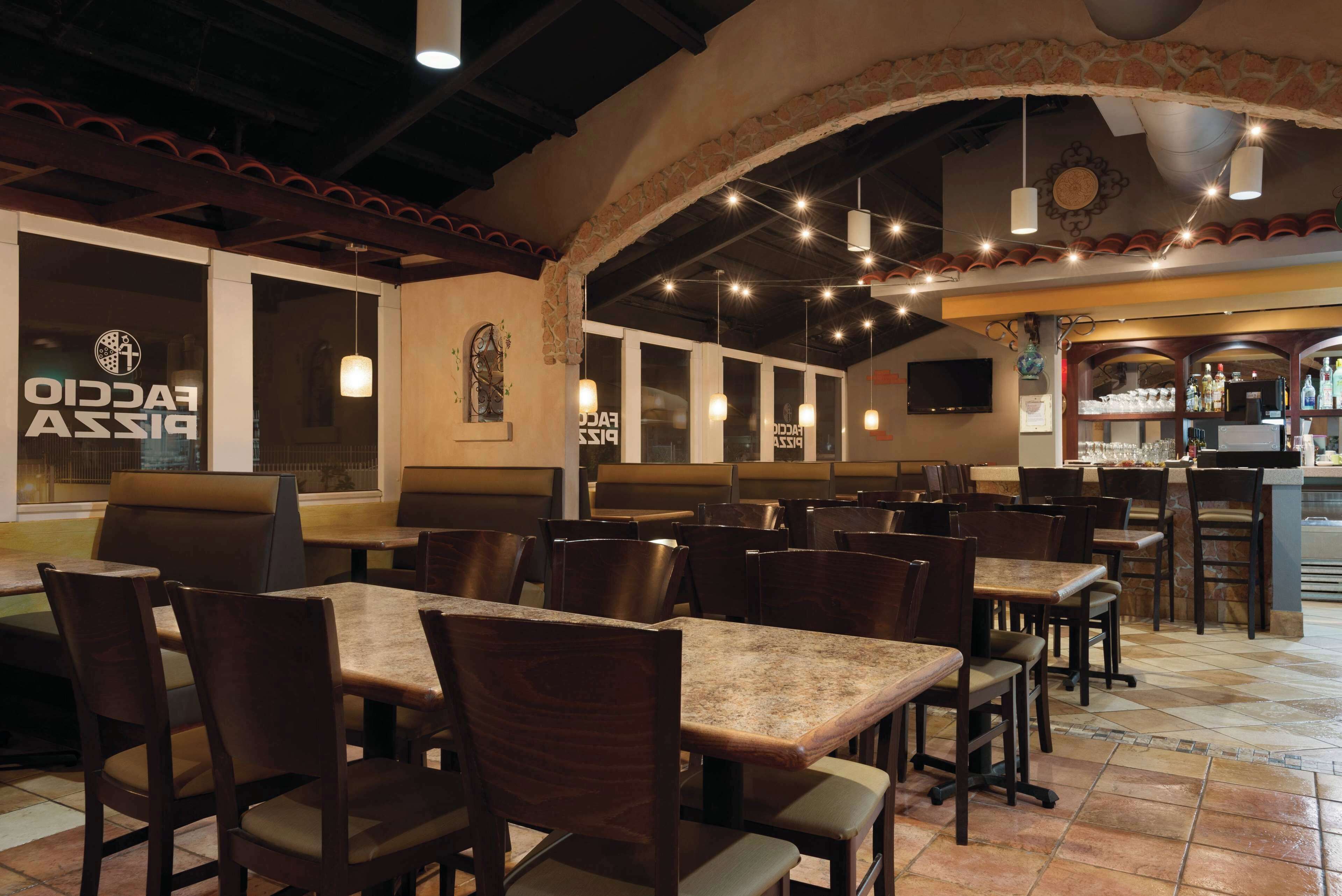 Un interior de restaurante con cabinas y mesas, paredes de piedra y luces colgantes.