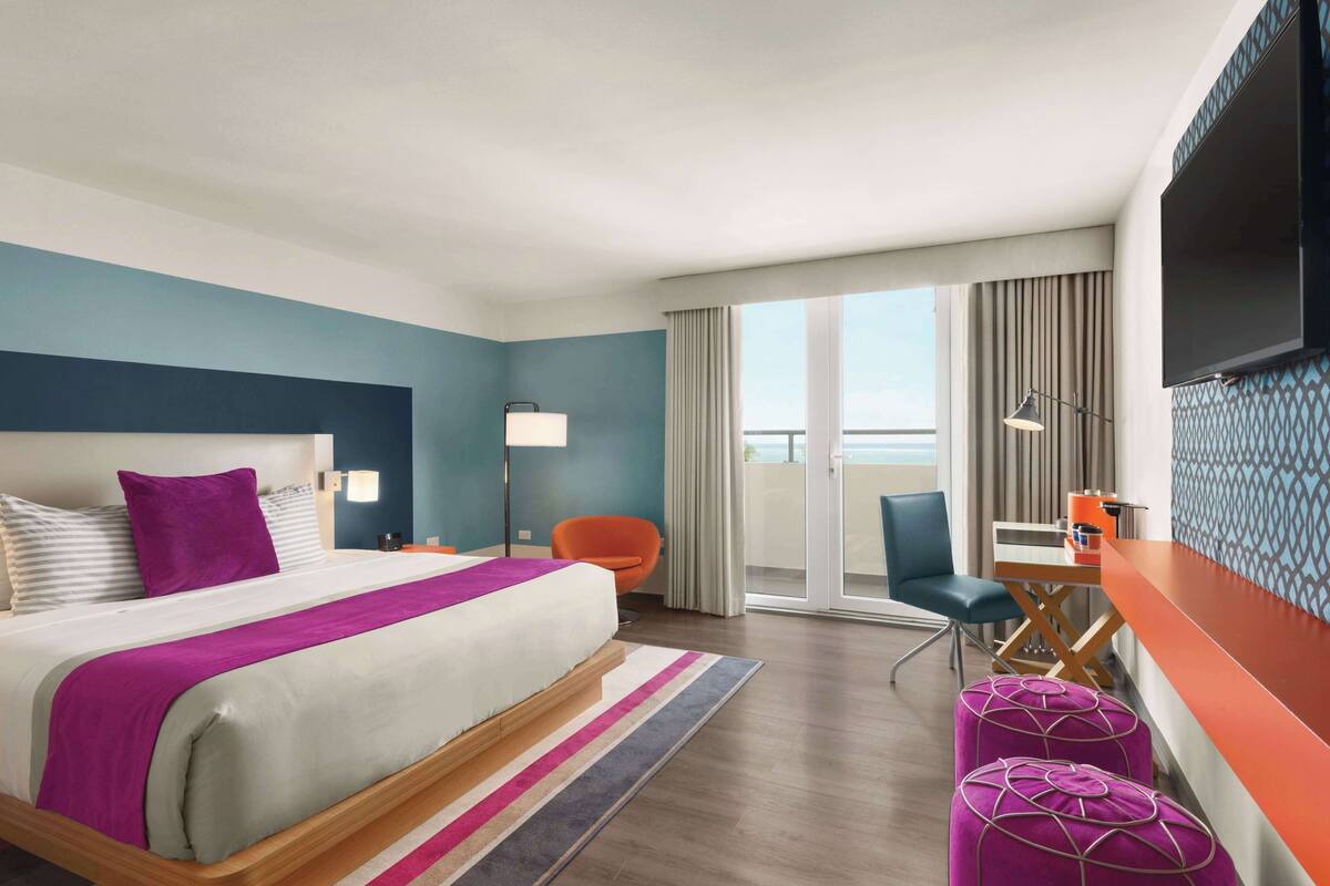 A hotel room with a bed, a desk, a chair, and a TV.