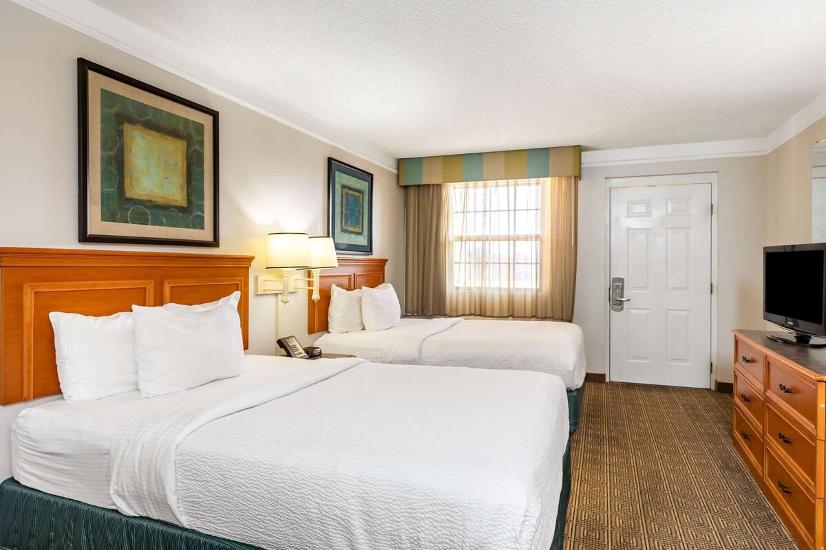 Una habitación de hotel con dos camas, televisión, cómoda y una puerta.