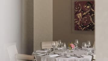 A dining table set with multiple wine glasses, cutlery, and a vase with flowers.