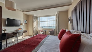 A hotel room with a bed, desk, chair, TV, and a view of the sea. - Grand Jersey Hotel & Spa (St. Helier)