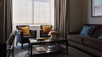 A modern living room with a sofa, armchairs, a coffee table, and a window with curtains.