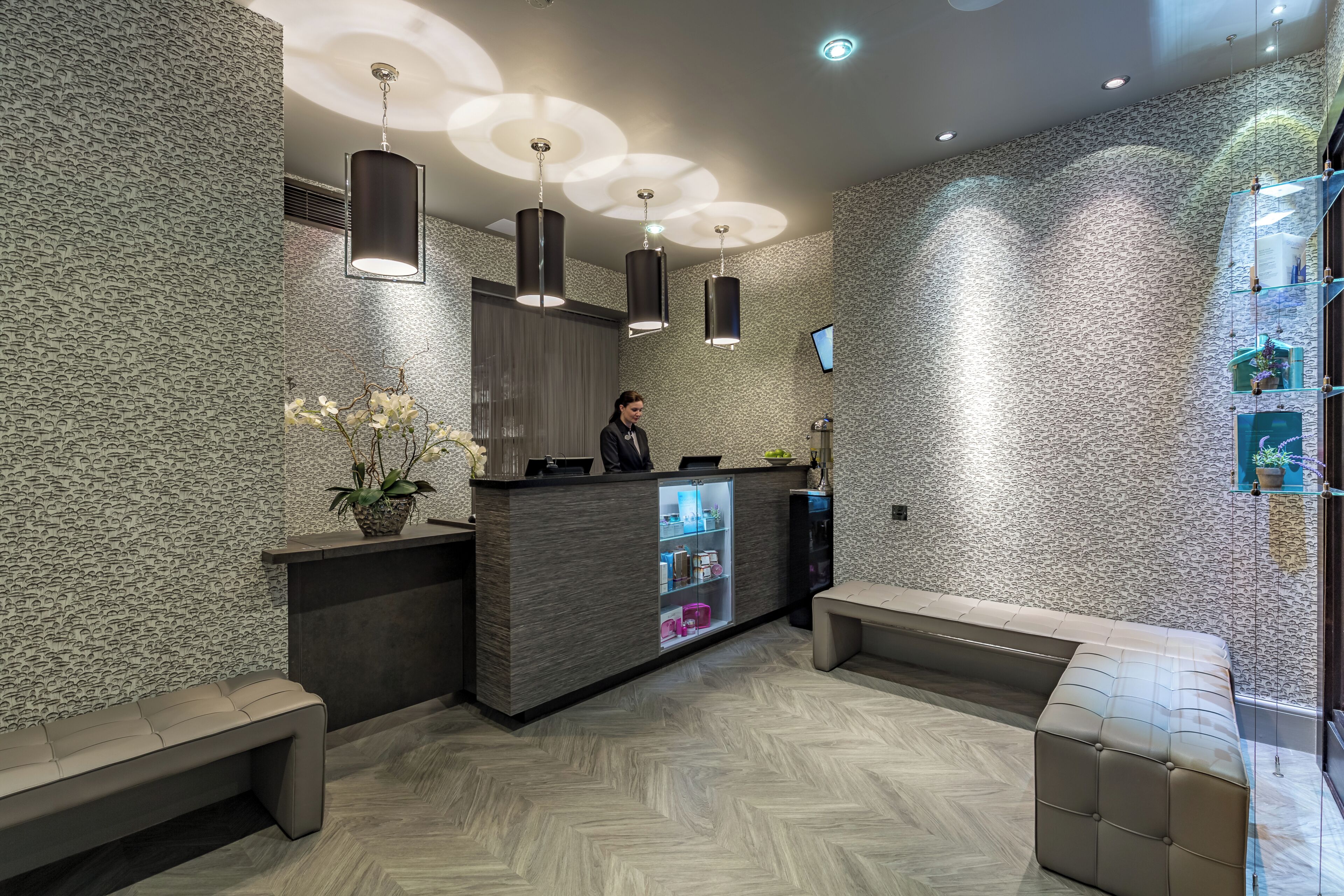 A reception area with a modern design, featuring a reception desk, seating, and decorative lighting.