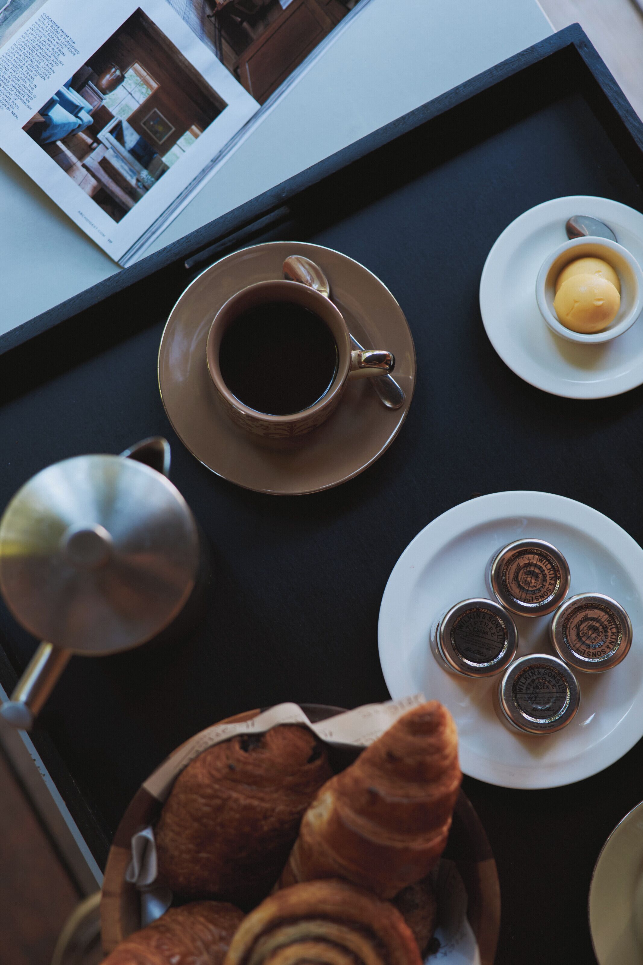 Una bandeja con una taza de café, un plato de pasteles y un libro.