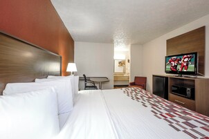 Una habitación de hotel con una cama grande, televisión, escritorio y espejo.