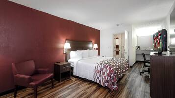Een hotelkamer met een bed, een bureau, een stoel en een televisietoestel.