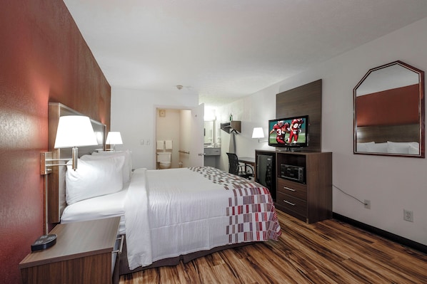 A hotel room with a bed, a television, a desk, and a mirror.