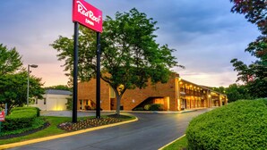 A Red Roof Inn with a brick building, a covered walkway, and a landscaped area with trees and flowers. - Red Roof Inn Edgewood (Edgewood)