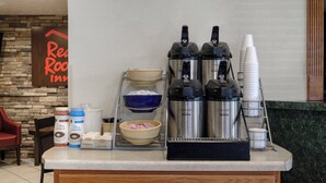 A coffee station with a coffee maker, creamer dispensers, and a bowl of sugar packets. - Red Roof Inn Edgewood (Edgewood)