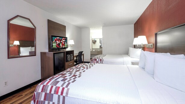 A hotel room with a large bed, a television, a desk, and a mirror. - Red Roof Inn Edgewood (Edgewood)