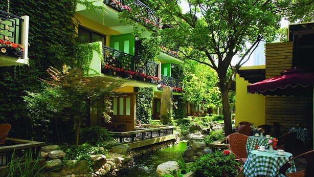 Un patio tranquilo con un estanque pequeño, mobiliario de exterior y un puente.