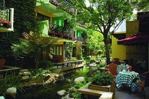 A serene courtyard with a small pond, outdoor seating, and a bridge. - Jianguo Hotel Beijing (Beijing)