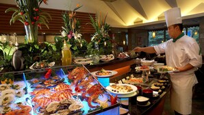 Exhibición de mariscos con diversos tipos de mariscos y crustáceos, un chef preparando platos, y un interior bien iluminado con plantas y un diseño moderno.