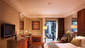 Habitación de hotel con cama, escritorio, televisor y vistas al exterior.