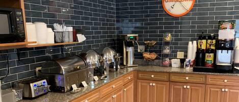 Une cuisine équipée d’une horloge, d’une machine à café, d’un grille-pain et de divers autres appareils de cuisine.