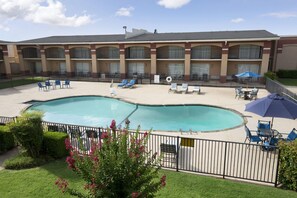A hotel with a swimming pool, outdoor seating, and a fenced patio area. - Howard Johnson by Wyndham Oklahoma City Airport/ Fairgrounds (Oklahoma City)