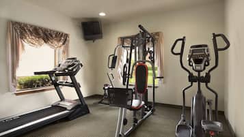 Un gimnasio con cinta de correr, elíptica y máquina de pesas.