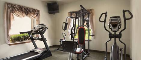 Un gimnasio con cinta de correr, elíptica y máquina de pesas.