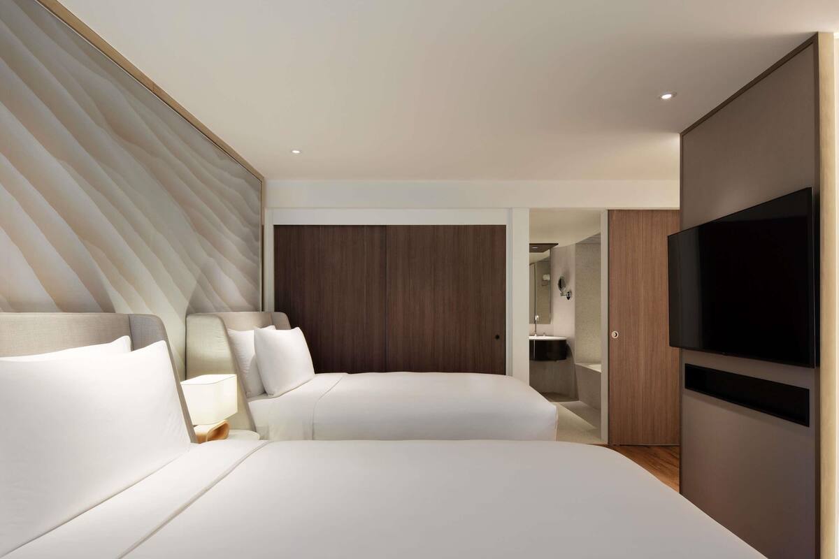 Ein modernes Hotelzimmer mit einem großen Bett, einem Fernseher und einem begehbaren Kleiderschrank.