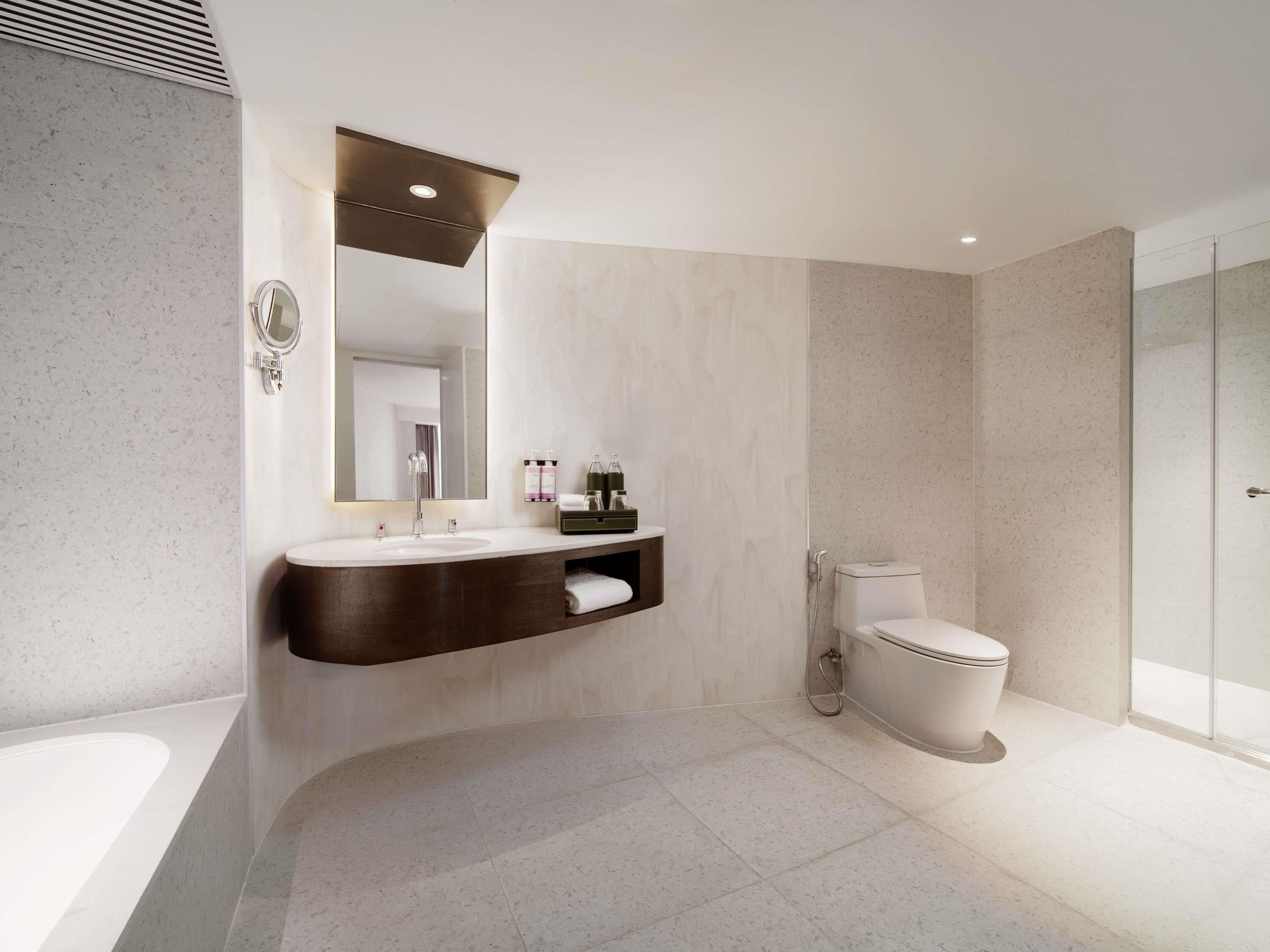 A modern bathroom with a freestanding bathtub, a vanity with a mirror, a toilet, and a shower area.