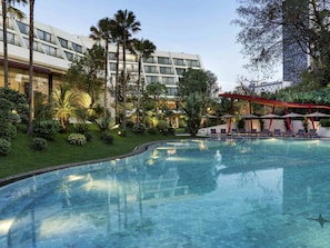 Una piscina al aire libre, sombrillas, sillones reclinables de piscina