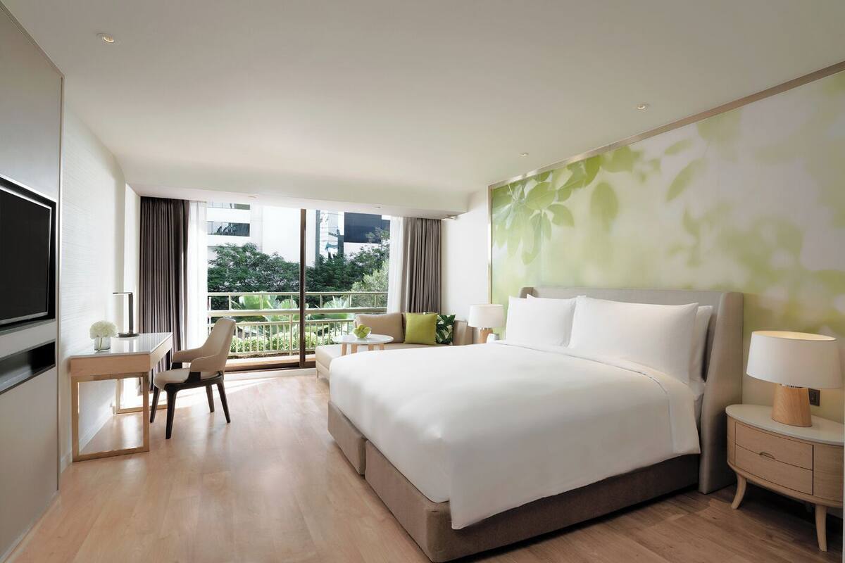 Ein modernes Hotelzimmer mit einem großen Bett, einem Schreibtisch und einem Fernseher.