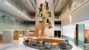 A spacious lobby with a central seating area, glass railings, and a modern ceiling design.