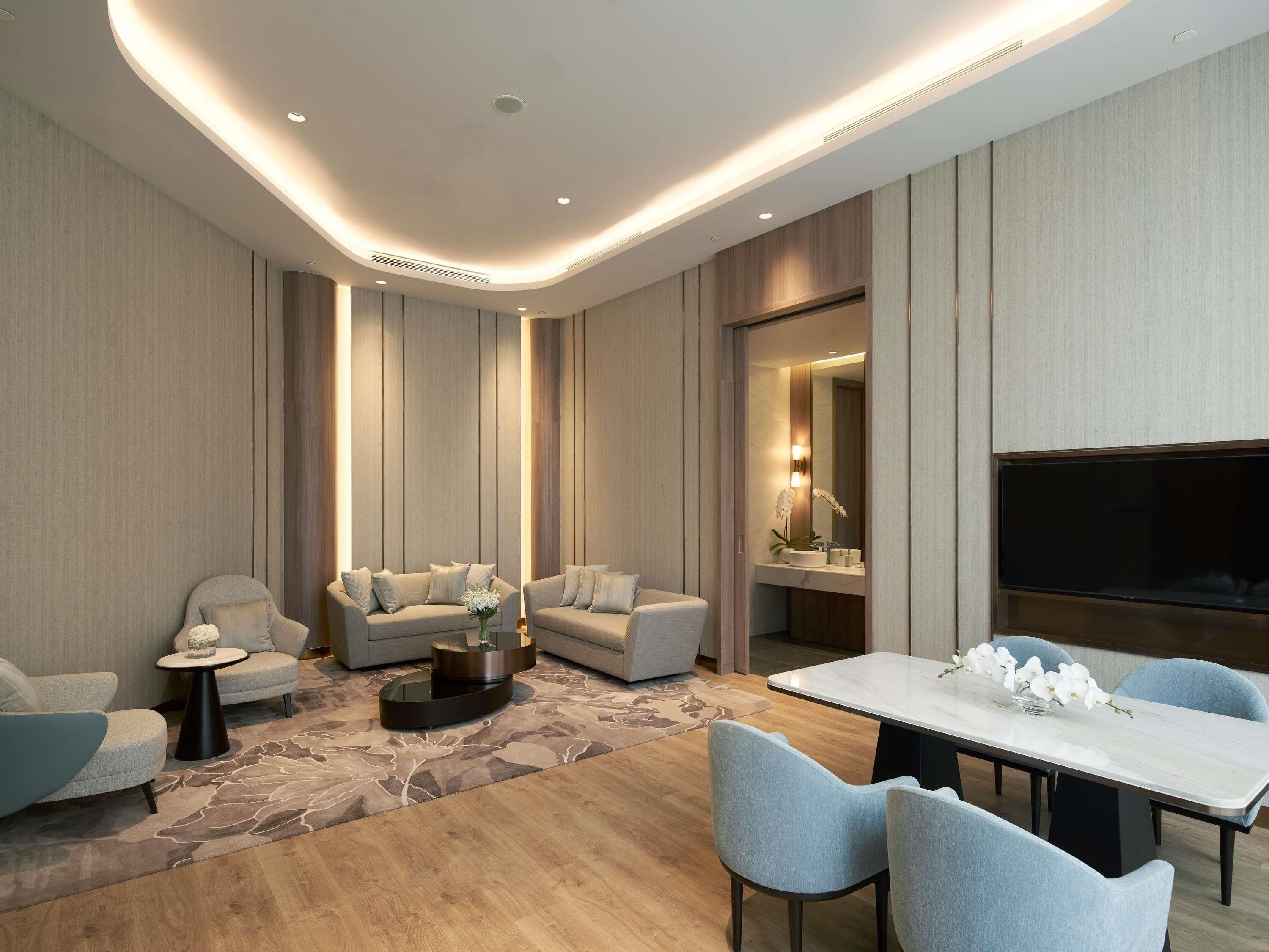 Una sala de estar moderna con un sofá, una mesa de centro, un televisor y un comedor con sillas.