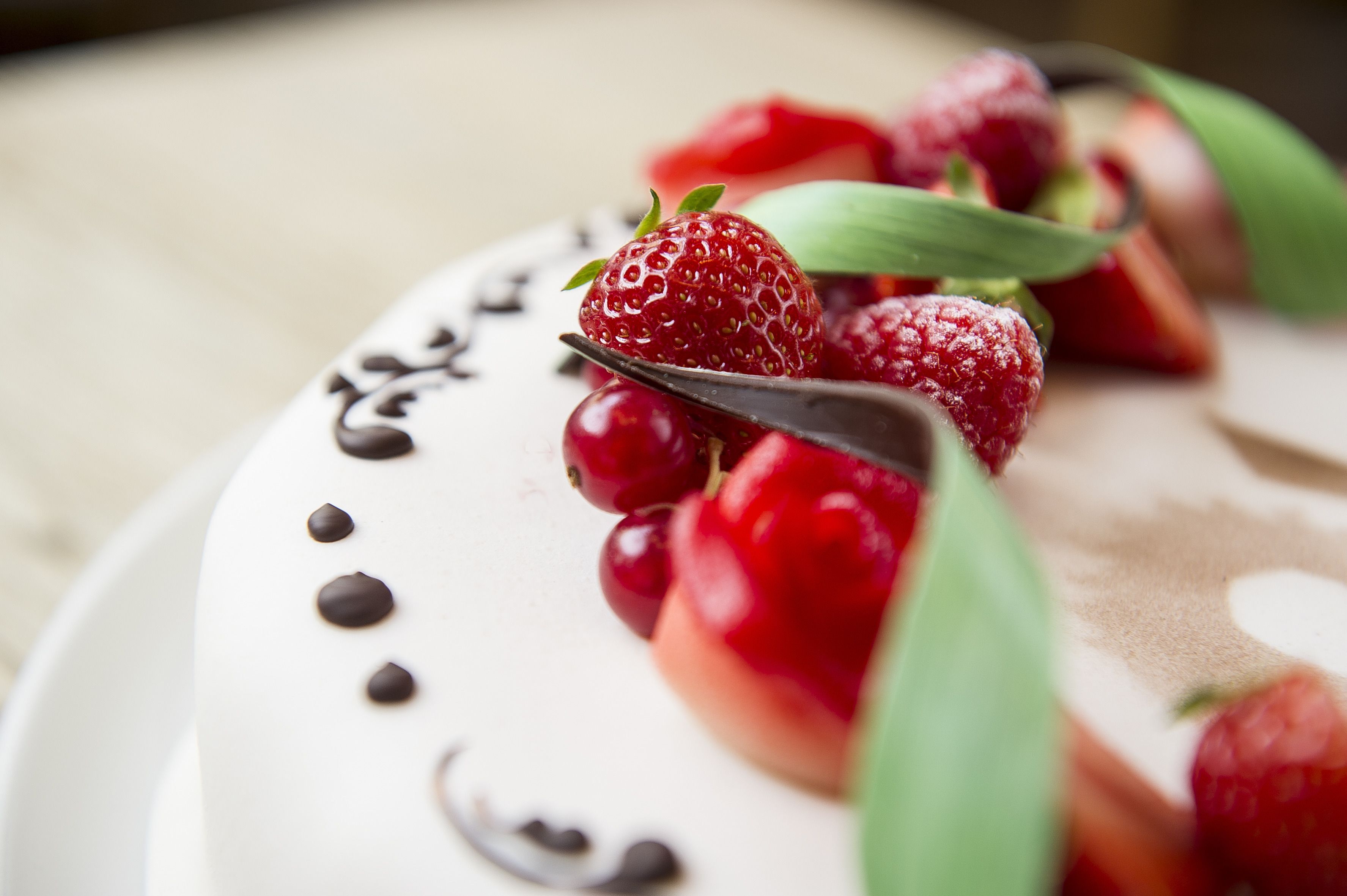 Un plato con fresas, frambuesas, hojas y trozos de chocolate.