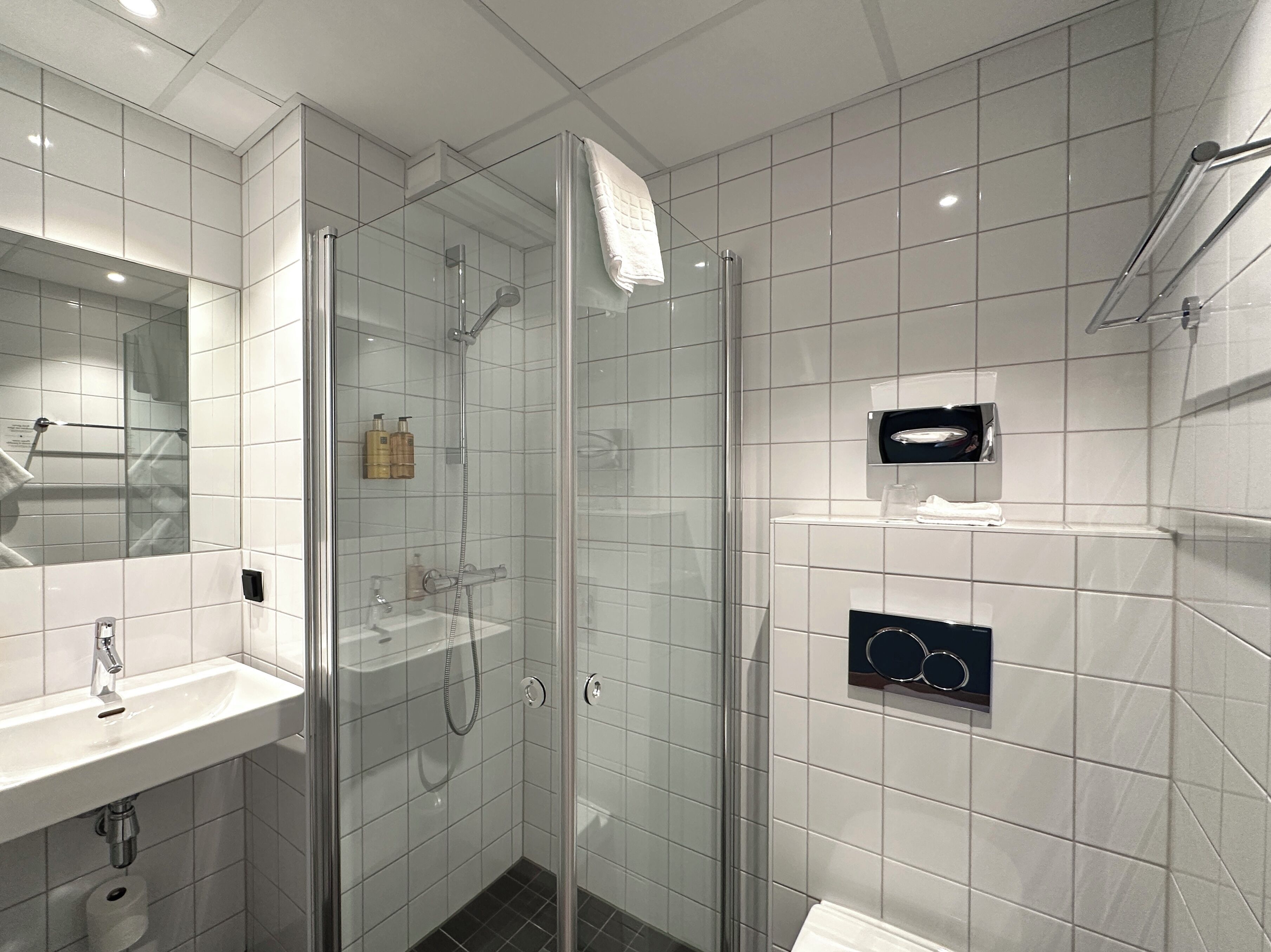 Un baño moderno con ducha de vidrio, lavabo blanco y espejo.