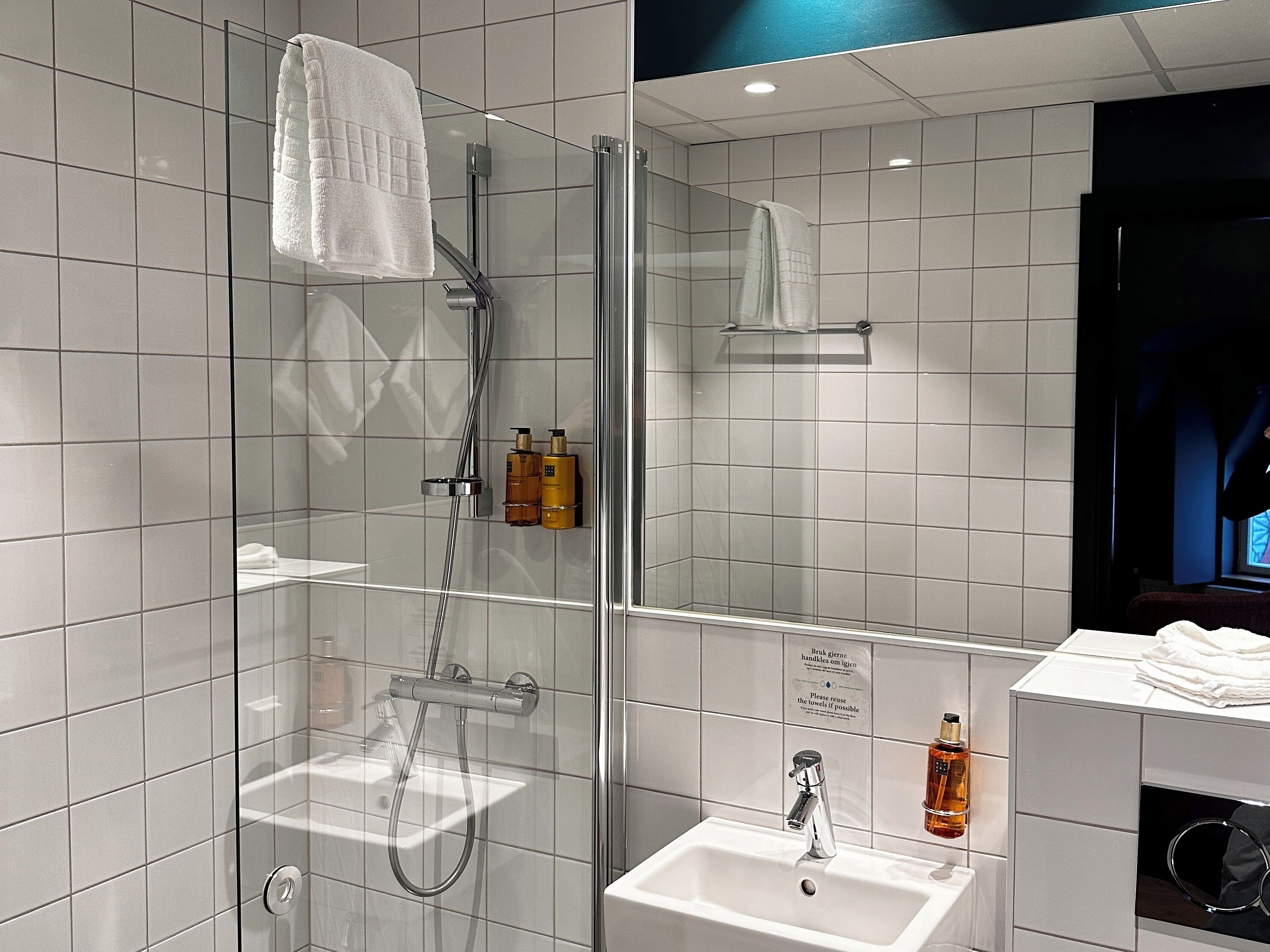 A modern bathroom with a glass-enclosed shower, a white sink, and a mirror.