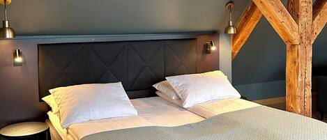 A bedroom with a large bed, two bedside tables, and a wooden ceiling structure.
