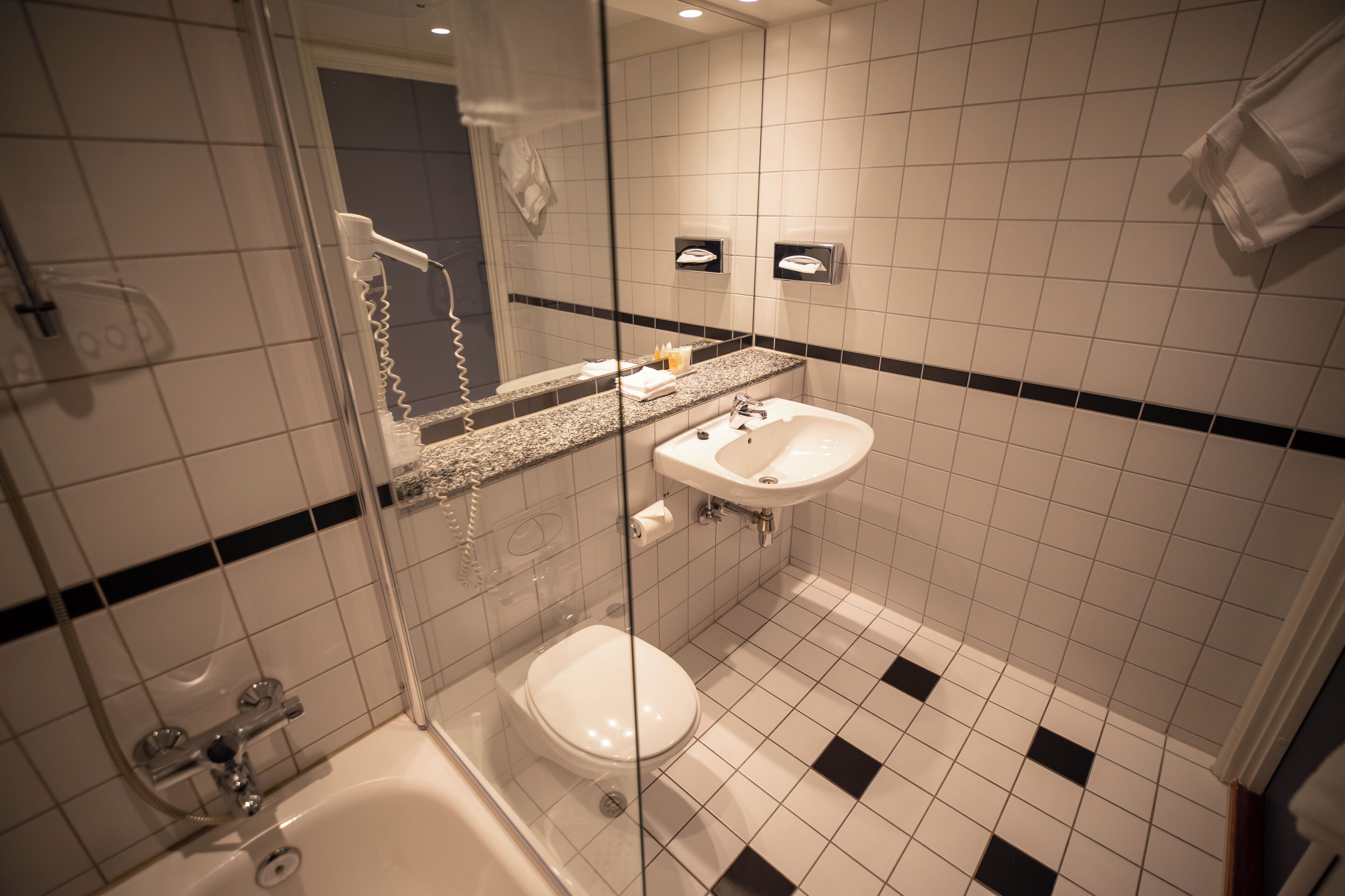 Un baño con cabina de ducha de vidrio, un lavamanos blanco y un inodoro.