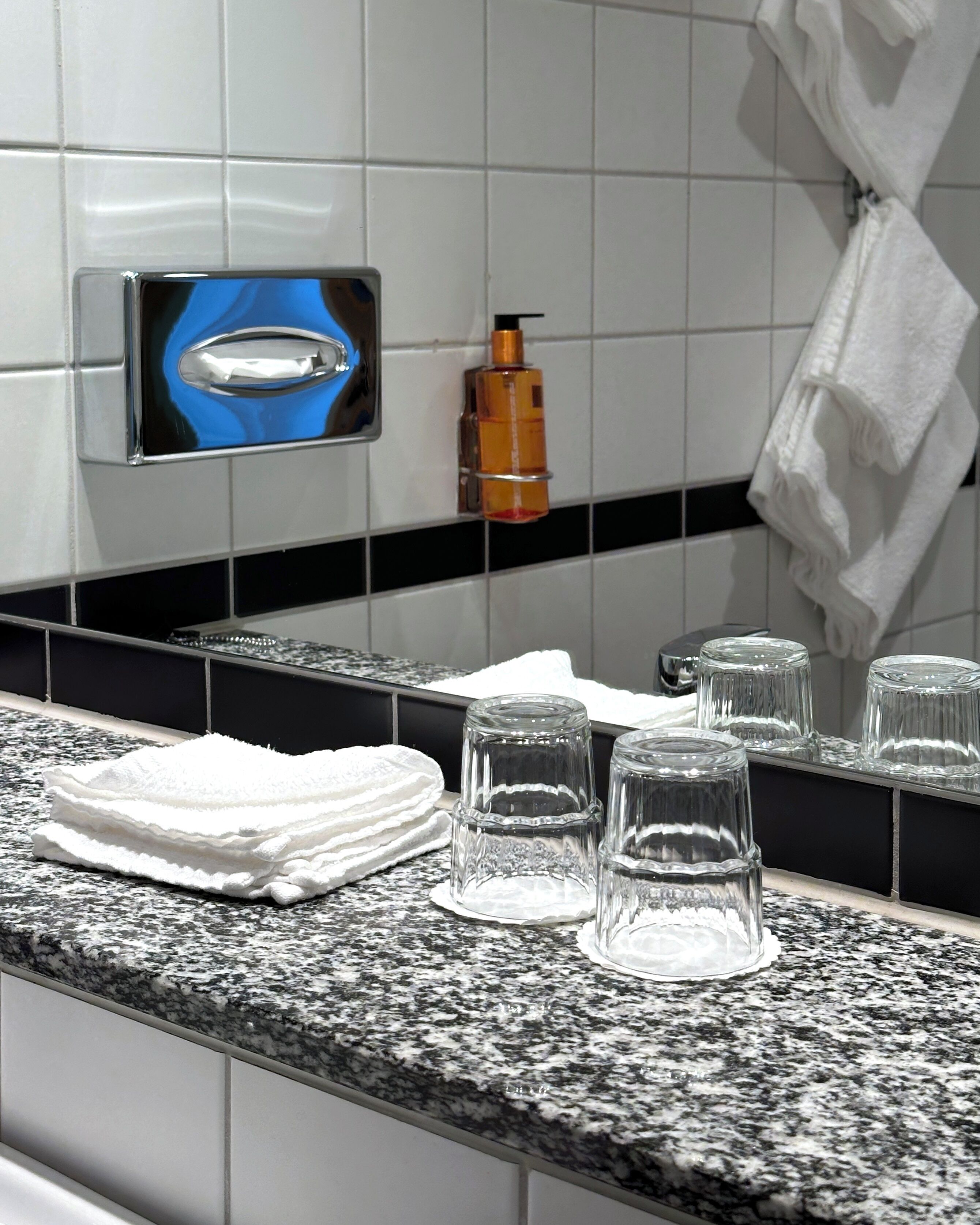 A bathroom counter with a towel stack, a soap dispenser, and a mirror.