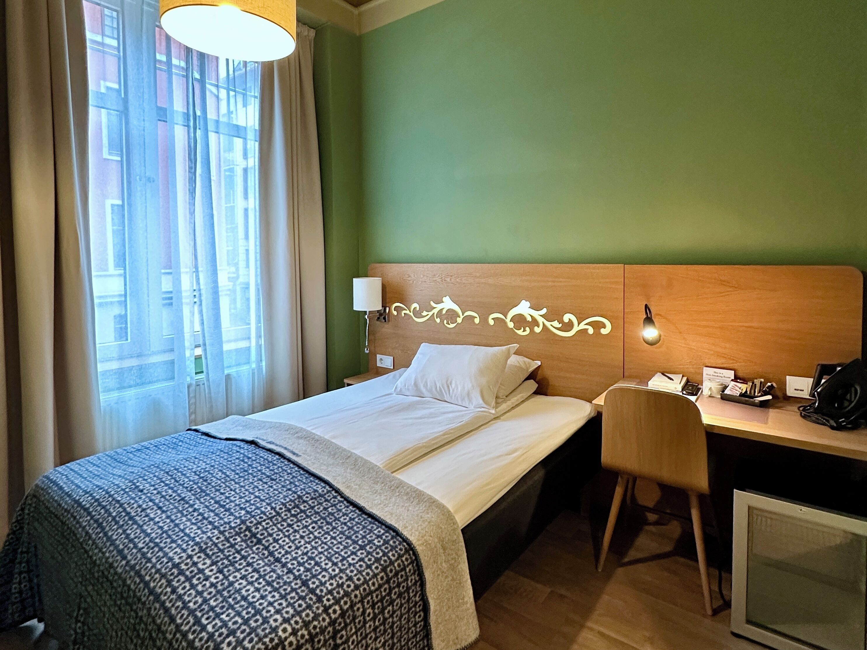 Una habitación de hotel con cama, escritorio, silla y televisor.