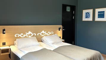 Ein Doppelbett mit weißen Bettwäsche, einem Holzkopfende und einer grauen Decke.
