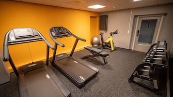 A gym with treadmills, a stationary bike, and a set of dumbbells.
