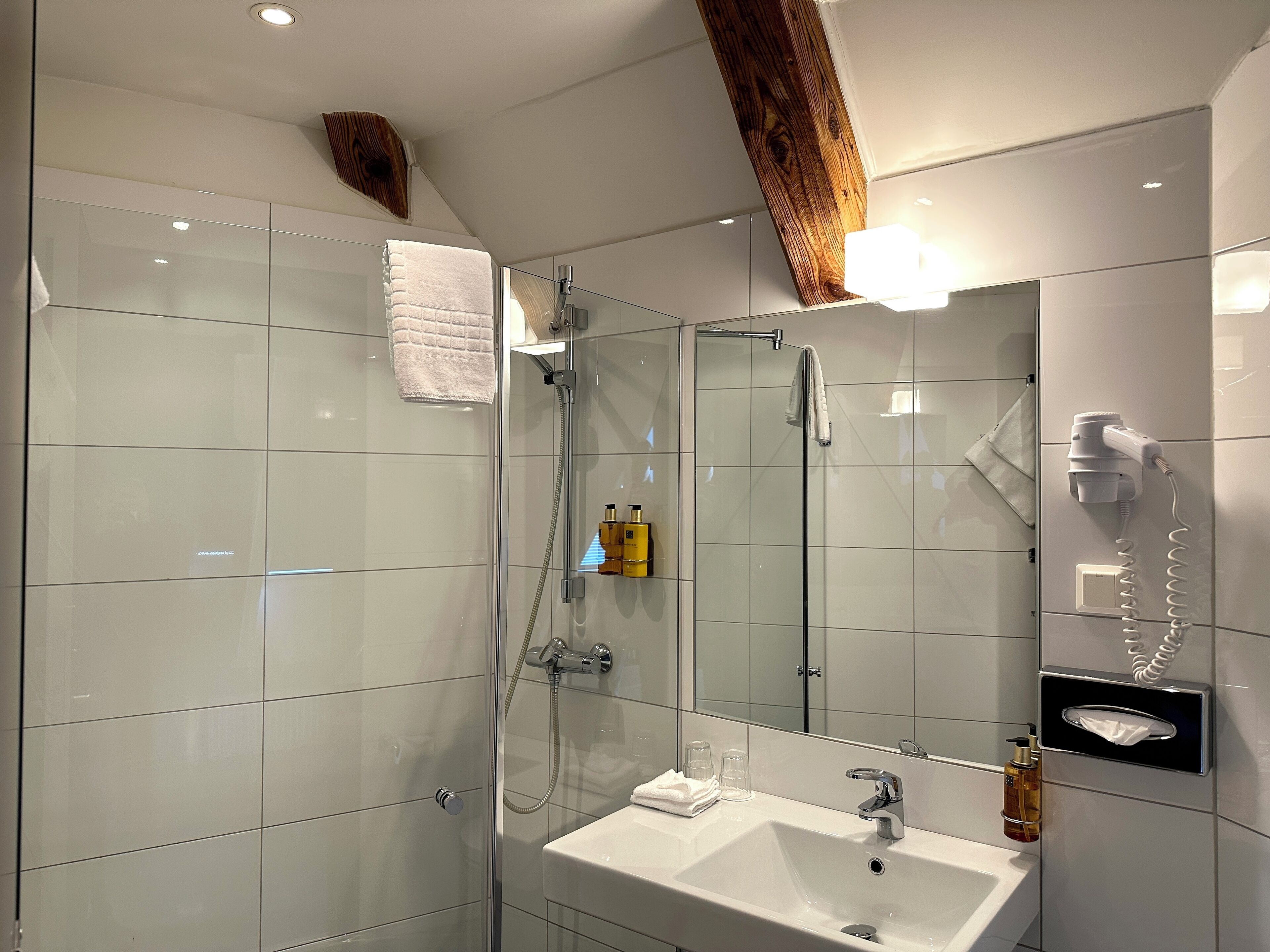 Une salle de bain moderne avec une douche à parois de verre, un lavabo blanc et un miroir.