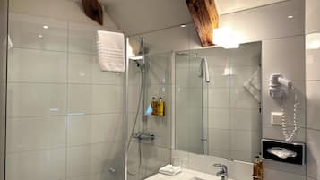 Ein modernes Badezimmer mit einer Duschkabine aus Glas, einem weißen Waschbecken und einem Spiegel.