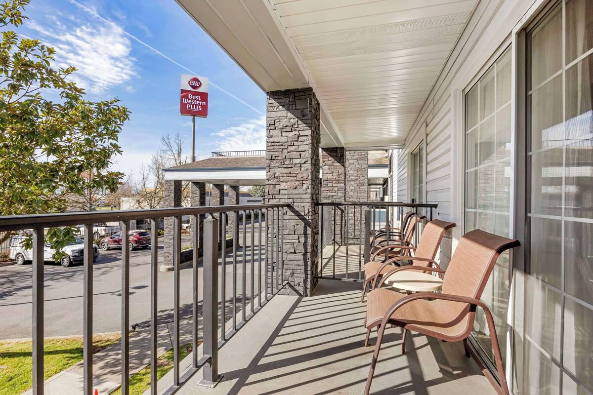 A hotel exterior with a covered outdoor seating area, stone pillars, and a Best Western Plus sign.