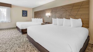 A hotel room with two beds, a wooden headboard, a nightstand, and a framed picture on the wall. - Best Western Plus Grand Manor Inn (Springfield)