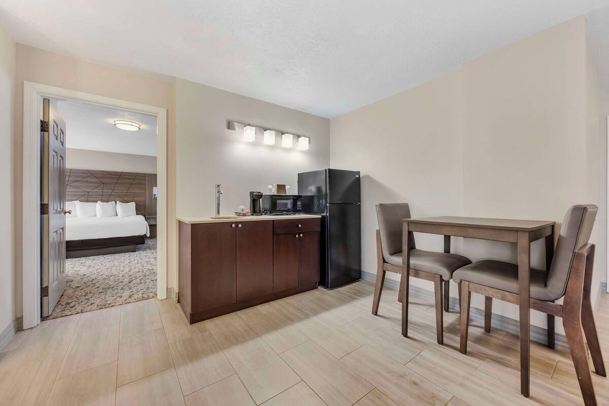 A compact hotel room with a kitchenette, a dining area, and a separate bedroom.