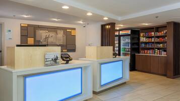 A reception area with a Holiday Inn Express sign, a digital display, and a snack vending machine.