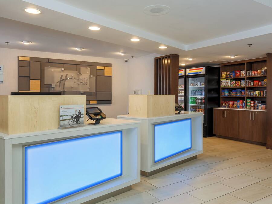 A reception area with a Holiday Inn Express sign, a digital display, and a snack vending machine.