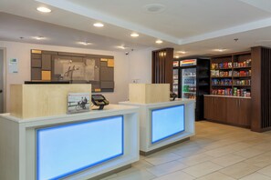 Vastaanottoalue, jossa on Holiday Inn Express -kyltti, digitaalinen näyttö ja automaatti, josta voi ostaa pientä purtavaa.
