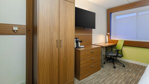 A hotel room with a wooden wardrobe, a desk with a chair, a flat-screen TV, and a window with blinds. - Holiday Inn Express Milwaukee-West Medical Center by IHG (Milwaukee)