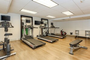 Un gimnasio con cintas de correr, elípticas y una máquina de remo.