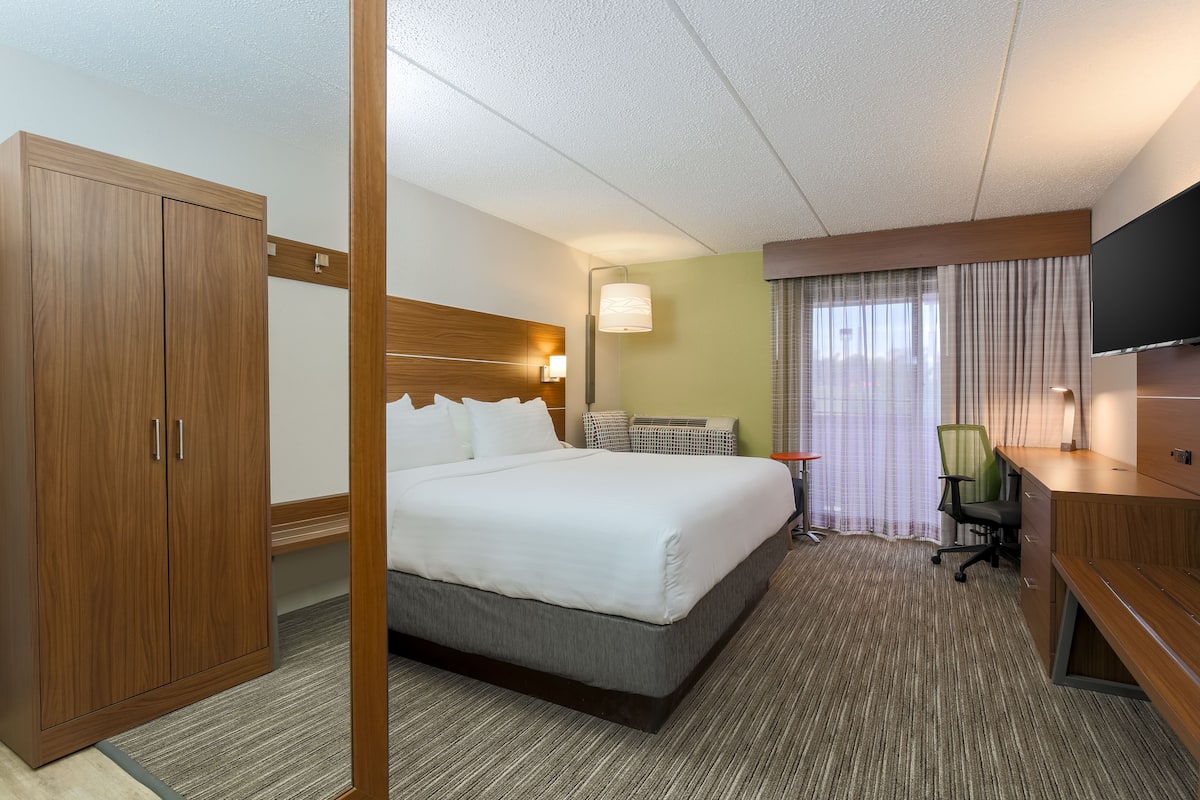 A hotel room with a large bed, a desk, a TV, and a wardrobe.