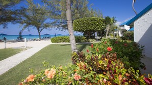 Un complexe hôtelier offrant une vue sur la plage, une pelouse bien entretenue et une grande variété de plantes tropicales.